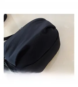 Close-up of the black nylon fabric texture and zip closure on the crossbody bag