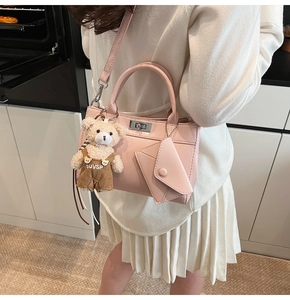 Détail d'un sac à main en cuir rose avec fermoir argenté et charmant ours en peluche