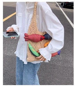 Detail of beige crochet tote bag featuring colorful fabric fish charms and woven texture