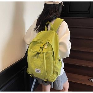 Detailed side view of mustard green nylon backpack showing large capacity and label
