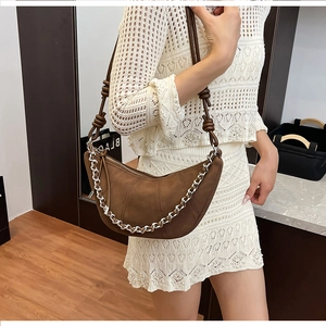 Close-up of brown suede half-moon bag with thick silver chain and knotted leather strap