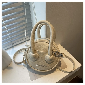 Detailed view of cream leather mini round bag with heart accents and top handles