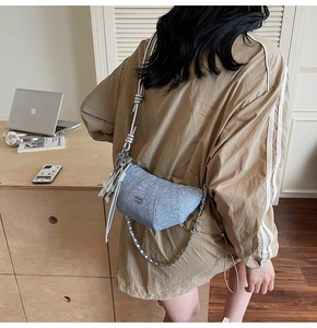Detail of light blue denim crescent bag featuring silver chain and star charm pendant