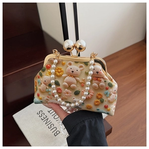 Detail of handmade crochet shell bag with mini 3D bear, floral accents and pearl handle