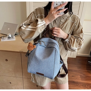 Detail of blue textured canvas backpack with double zipper and plush bear pendant