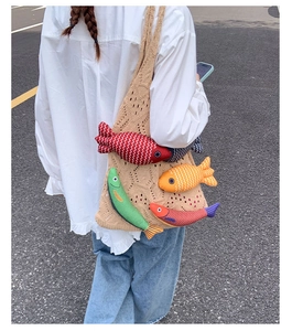 Detail of crochet knit tote bag featuring colorful plush fish charms and woven texture