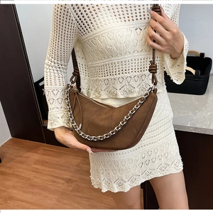 Close-up of brown suede half-moon bag with chunky silver chain and knot strap detail