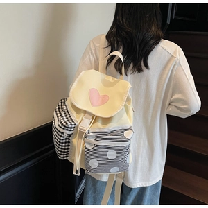 Detail view of canvas backpack with heart patch and mixed patterns worn by a model