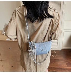 Blue denim half-moon bag with silver chain and star charm shown on a model's back