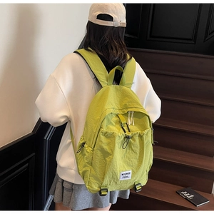 Side view of a green nylon backpack featuring adjustable drawstring and woven label