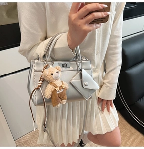 Détail du sac argenté avec fermoir métallique, ours en peluche et pochette enveloppe pour femme chic