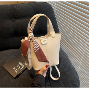 Detail view of cream lychee pattern handbag with a stylish red houndstooth scarf ornament