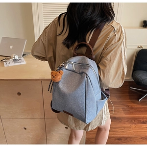 Blue denim texture backpack with brown leather straps and a cute plush bear pendant