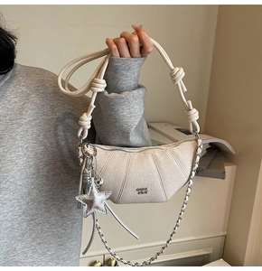 Detail of off-white lychee grain crescent bag with chain strap and star charm accessory