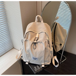Detail view of cream nylon backpack with side pockets and a stylish waswac rules tag