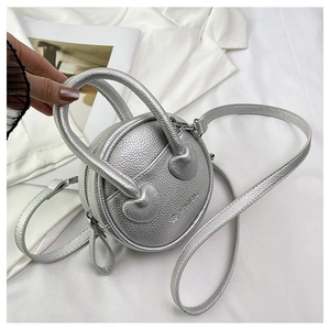 Detail of silver round mini crossbody bag with litchi texture and fashion engraving