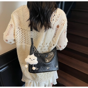 Détail du sac bandoulière plissé noir avec clous papillon et charm en peluche blanche