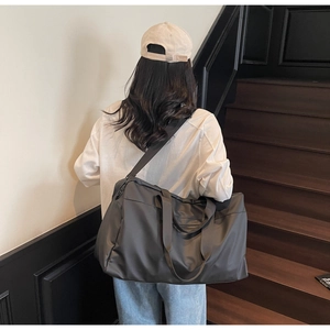 Vista posteriore di una modella con borsa da viaggio grigia su una scala moderna