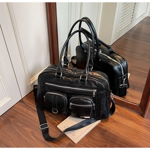 Dettaglio borsa da viaggio in pelle nera con doppie tasche e tracolla regolabile