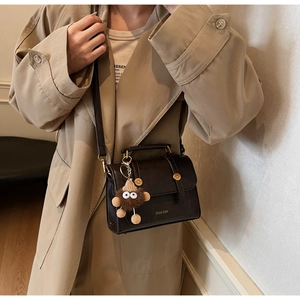 Detail view of vintage dark brown faux leather bag with gold buckle and plush charm