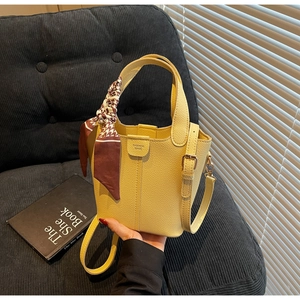 Detail of yellow bucket bag with lychee texture leather and dogtooth pattern silk scarf