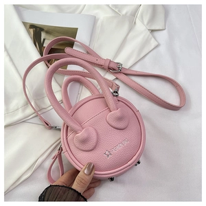 Detail view of pink round mini bag featuring pebble texture leather and metal feet studs