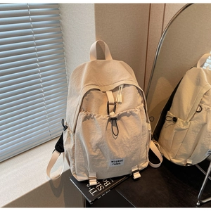 Detail of off-white nylon backpack with drawstring pocket and black carabiner clip