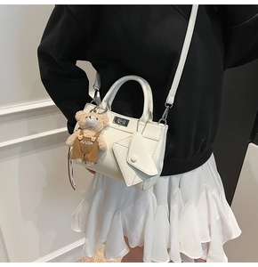 Détail d'un sac à main blanc en cuir avec fermoir en métal et pendentif ours