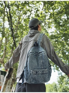 Detailed back view of vintage wash denim backpack worn outdoors in a natural setting