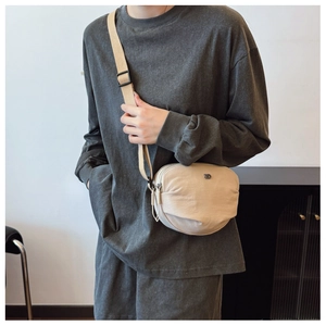 Detail of beige canvas crossbody bag with adjustable wide strap and dual zipper closure