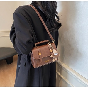 Brown vintage faux leather crossbody bag with cute plush toy pendant on black blazer
