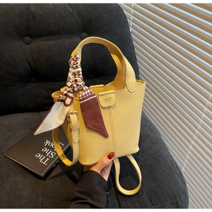 Detailed macro of yellow litchi pattern bucket bag with decorative geometric silk scarf