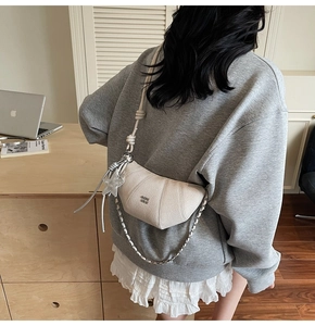 Close-up of beige crescent bag featuring lychee grain leather and silver star chain