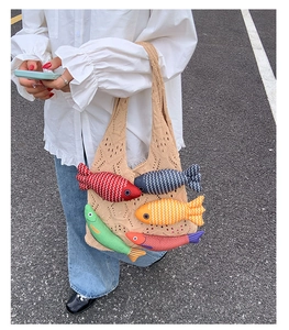 Detailed close-up of knit tote bag featuring colorful stuffed fish charms and fringe trim