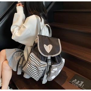 Detail of a black nylon backpack featuring a white heart motif and striped side pockets