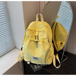 Detail view of bright yellow nylon backpack with drawstring pocket and mirror reflection