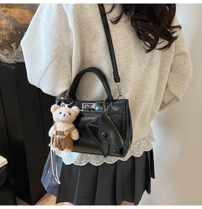 Détail du sac bandoulière noir en similicuir avec serrure argentée et ours en peluche