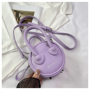 Close-up of lilac round mini bag with litchi texture and silver metallic studs