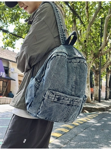 Close-up of retro washed denim backpack featuring functional front pocket and side pockets