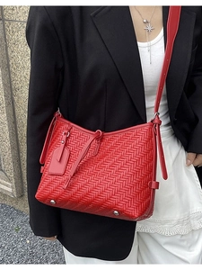 Bright red woven shoulder bag with herringbone texture and leather tag in street style