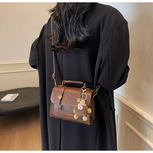Detail of vintage brown leather handbag featuring gold hardware and logo with shoulder strap