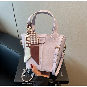 Close-up of lilac pebbled leather bucket bag with houndstooth silk scarf and gold hardware