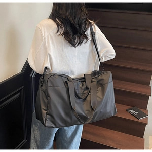 Borsa da viaggio nera impermeabile con tracolla indossata da una persona su una scala