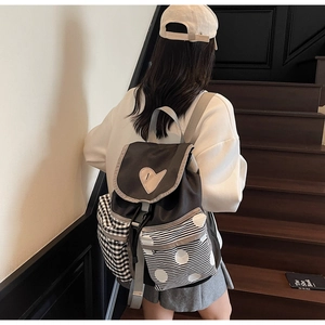 Detail of color-block backpack showing heart patch and mixed pattern pockets on stairs