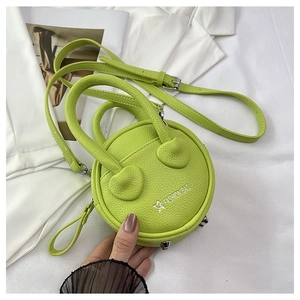 Detail view of mini lemon green crossbody bag with heart patches and metal feet