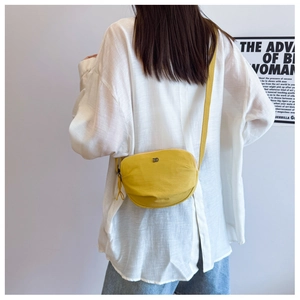 Chic yellow canvas half-moon crossbody bag shown on model with adjustable strap