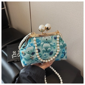 Detailed macro of blue shell bag featuring 3D bear floral prints and pearl chain handle