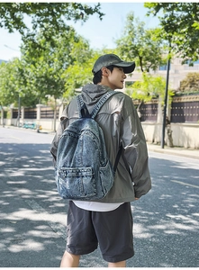 Outdoor view showing the back profile of the vintage washed denim backpack on a model