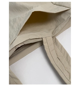 Detailed close-up of internal pocket and reinforced stitching on beige canvas tote bag