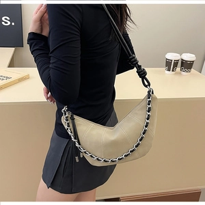 Detail of beige crescent bag with contrast stitching and metallic chain strap